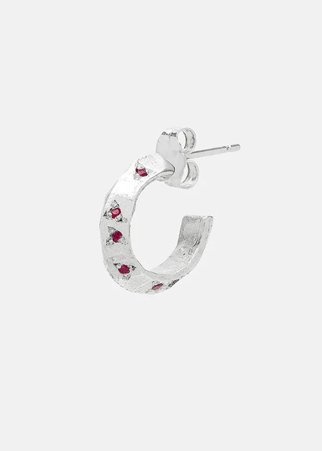 Silver hoop earring with embedded red gemstones on a white background