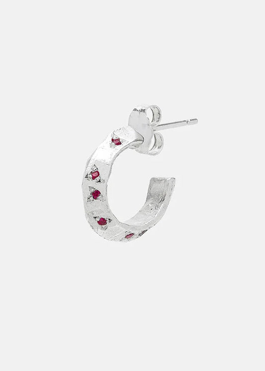Silver hoop earring with embedded red gemstones on a white background