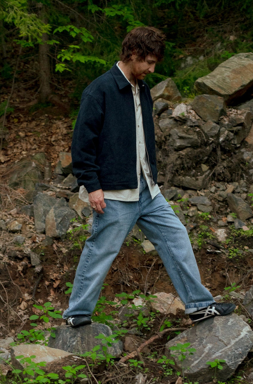 Man walking on rocks with a dog in a forest setting