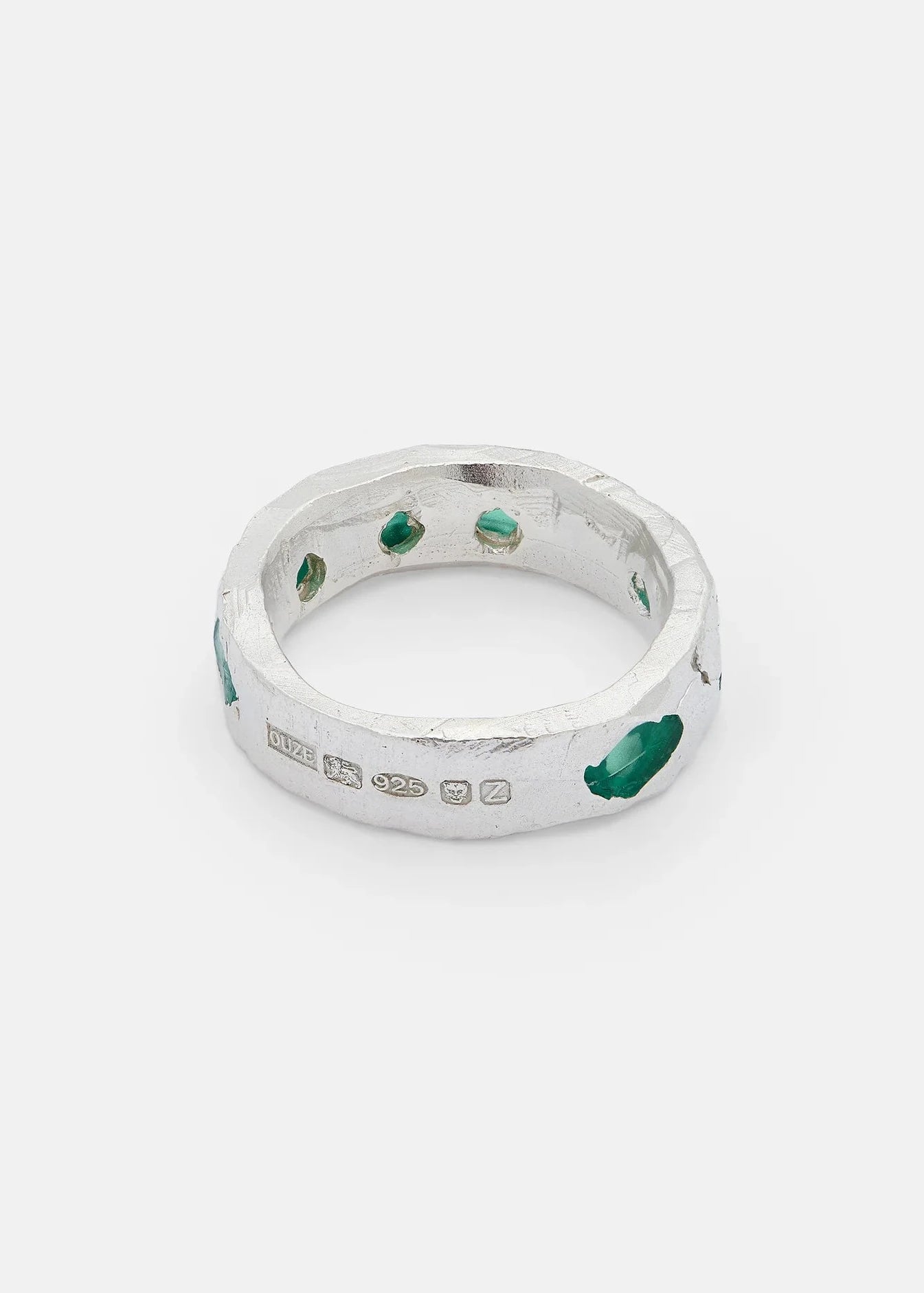 Silver ring with green gemstones on a white background
