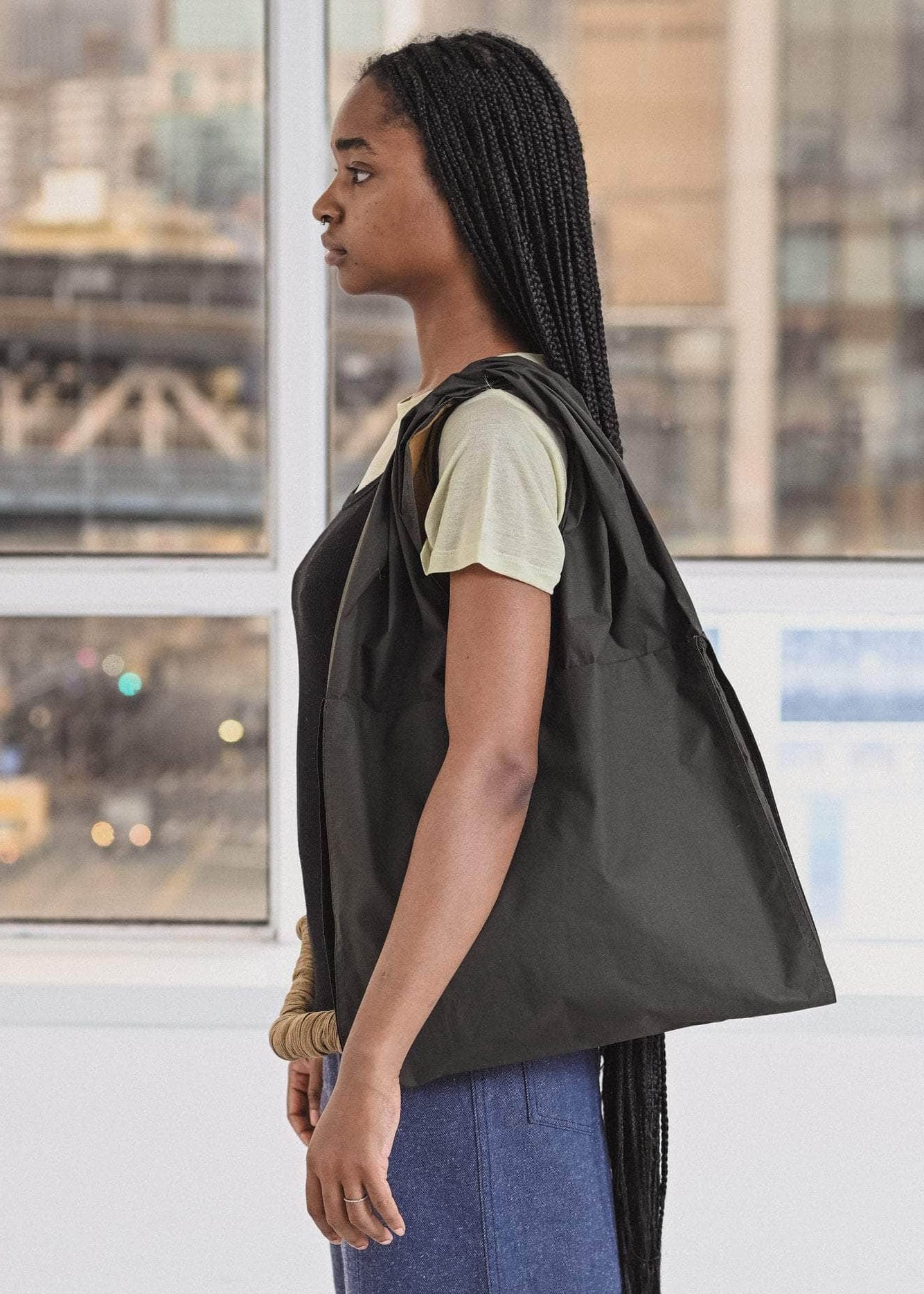 Woman carrying a large black tote bag in an urban setting