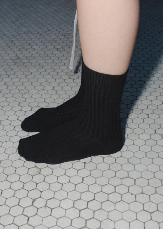 Black socks worn on a tiled floor