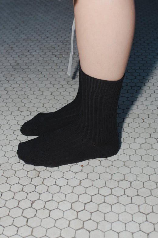 Black socks worn on a tiled floor