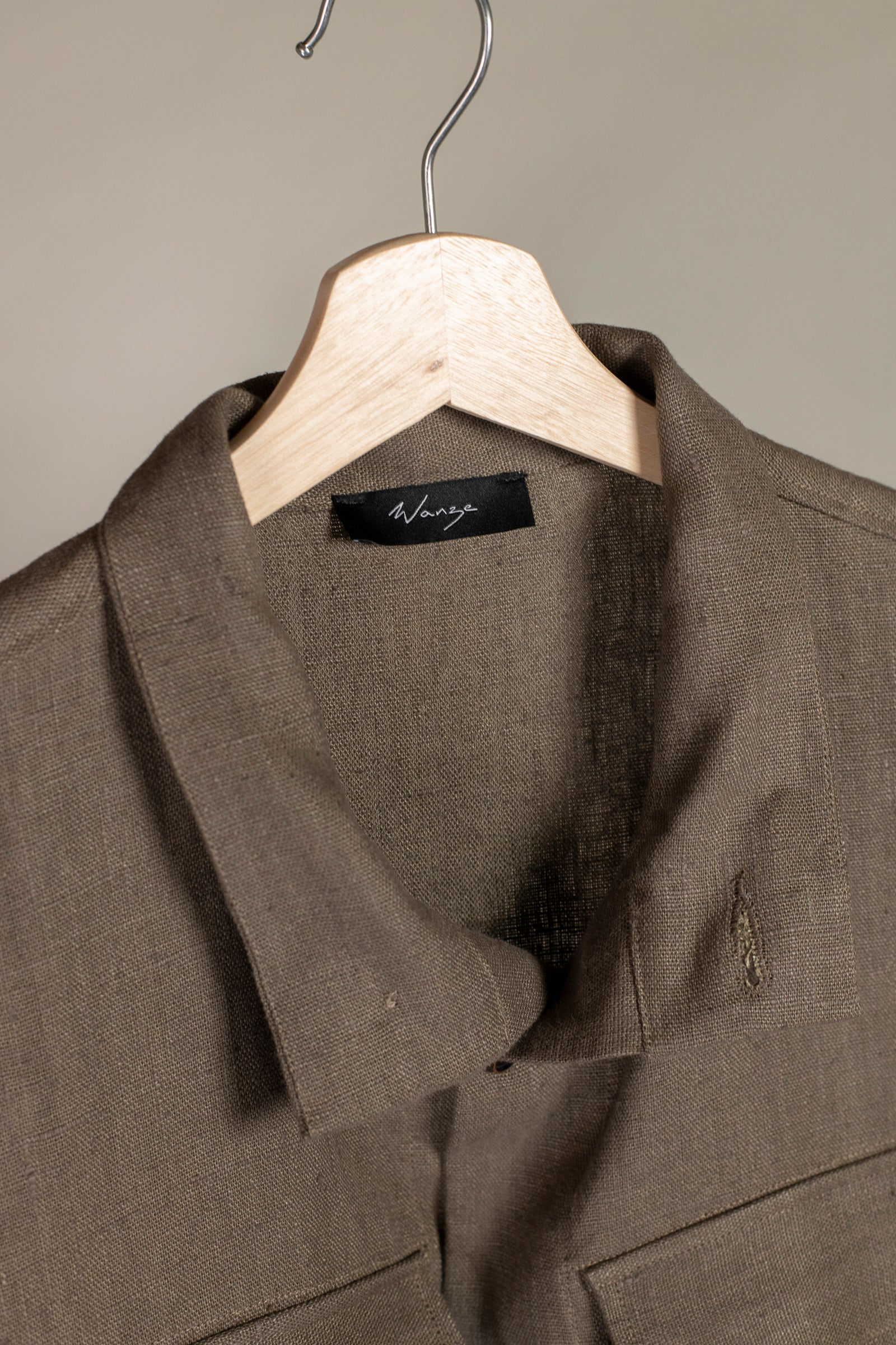 Close up of collar and tag of Wanze men's natural linen field jacket in brown