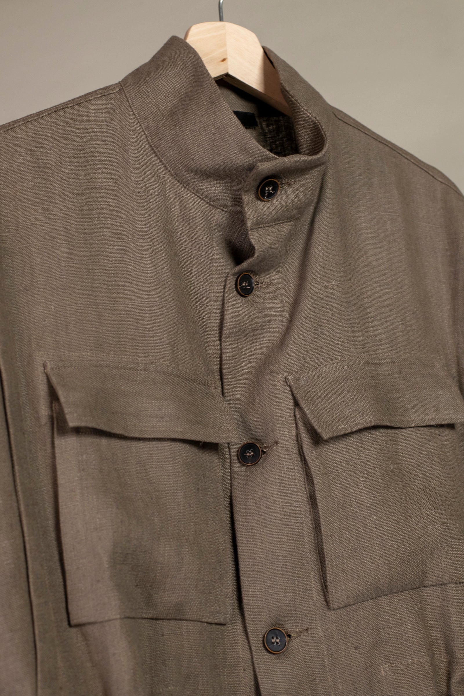 Close up on buttoned up collar on Wanze men's natural linen field jacket in brown